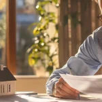 Un homme lisant un papier A4 assis à son bureau